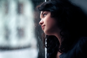 Beautiful girl looks out of the window. On its lips an easy smile, and behind a window a rain.